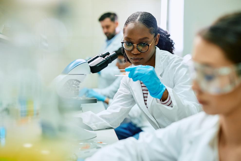 A woman scientist is looking through a microscope.